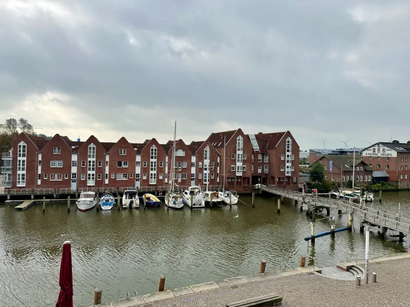 Blick von der Terrasse über das Hafenbecken auf die Giebelhäuser und die Boote am Steg